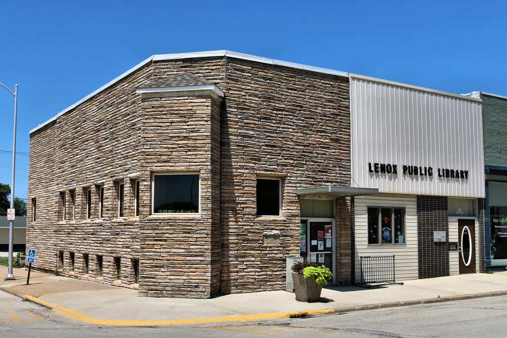 An exterior view of a bright, modern public library with high ceilings and large windows filling the space with natural light.